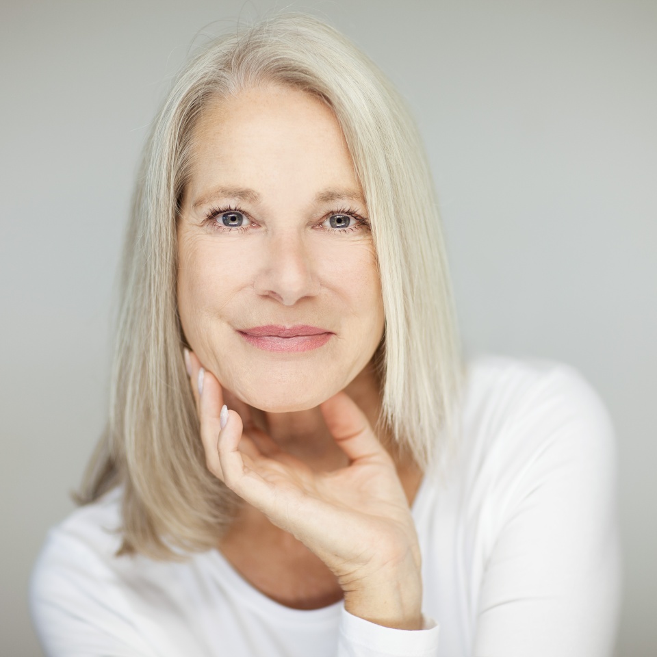 stunning beautiful and self confident best aged woman with grey hair smiling into camera, portrait with white background