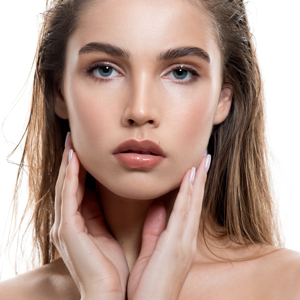 Beautiful young woman with clean perfect skin and wet glossy lips. Portrait of beauty model with natural make up, lifted brows and long eyelashes. Spa, skincare and wellness.
