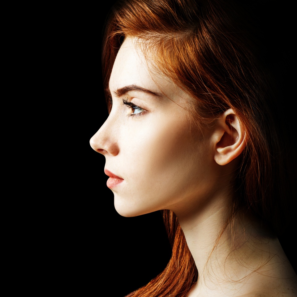 Beauty portrait of redhead woman. Over black background.