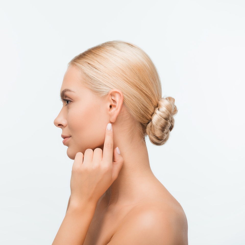 side view of naked young woman pointing with finger at ear isolated on white