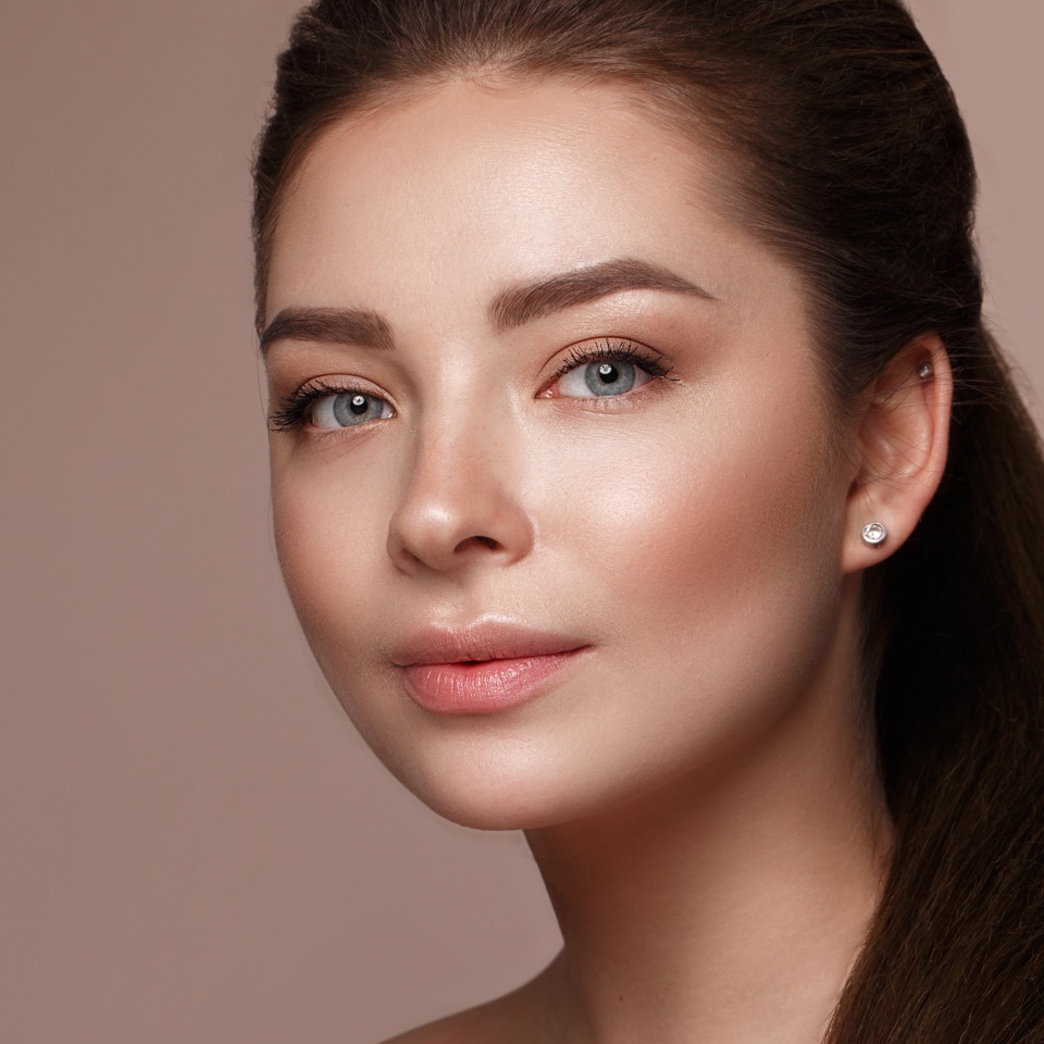 Beautiful young girl with natural nude make-up with cosmetic in hands. Beauty face. Photo taken in studio