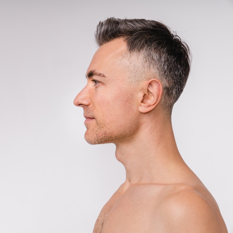 Side view shot of an attractive mature naked man isolated over white background