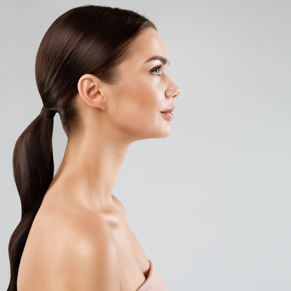 Beauty Model Perfect Face Profile. Brunette Woman with Healthy Smooth Facial Skin and Hair over White. Beautiful Girl Side view Portrait with Full Lips and Natural Make up. Female Plastic Surgery