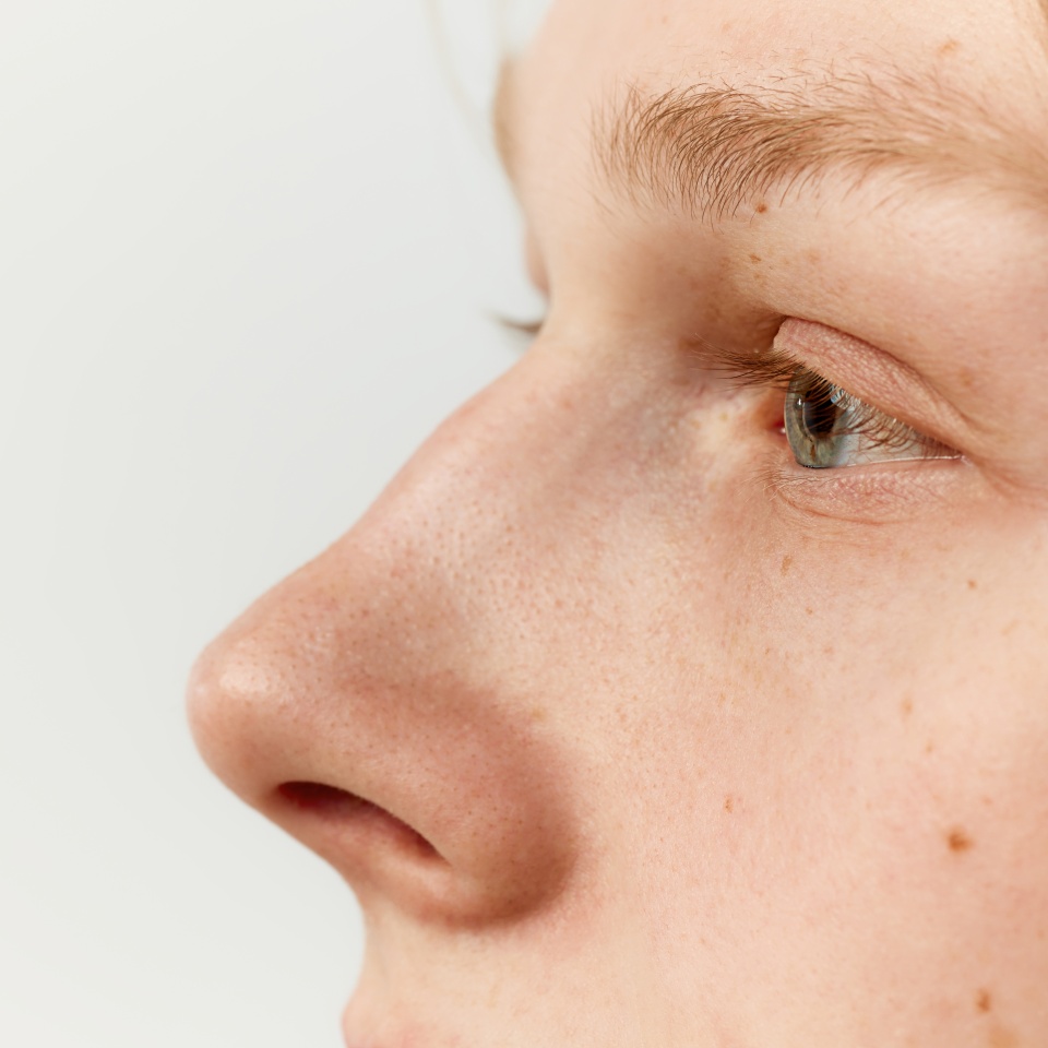 Side view close-up image of male face, eyes and nose. Young redhead model posing over grey studio background. Concept of men's health, body and skin care, hygiene and male cosmetology