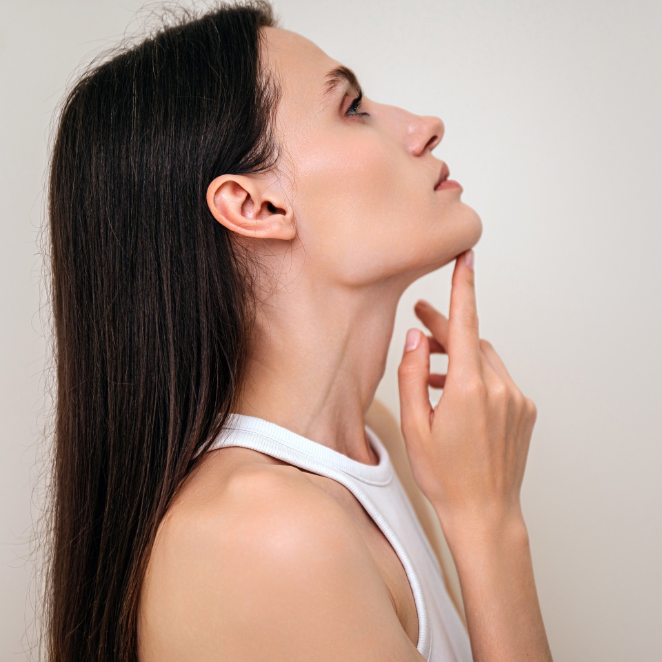 Aesthetic medicine, dermatology concepts. Profile view of woman with perfect face contour touching her neck. Cosmetology clinic with procedure for skincare, rejuvenation, wellness and spa treatment