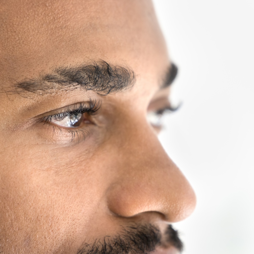 Handsome young African man looking away banner shot. Serious attractive Black guy upper face close up cropped portrait. Male model advertising eyes care, eyesight checkup, vision correction