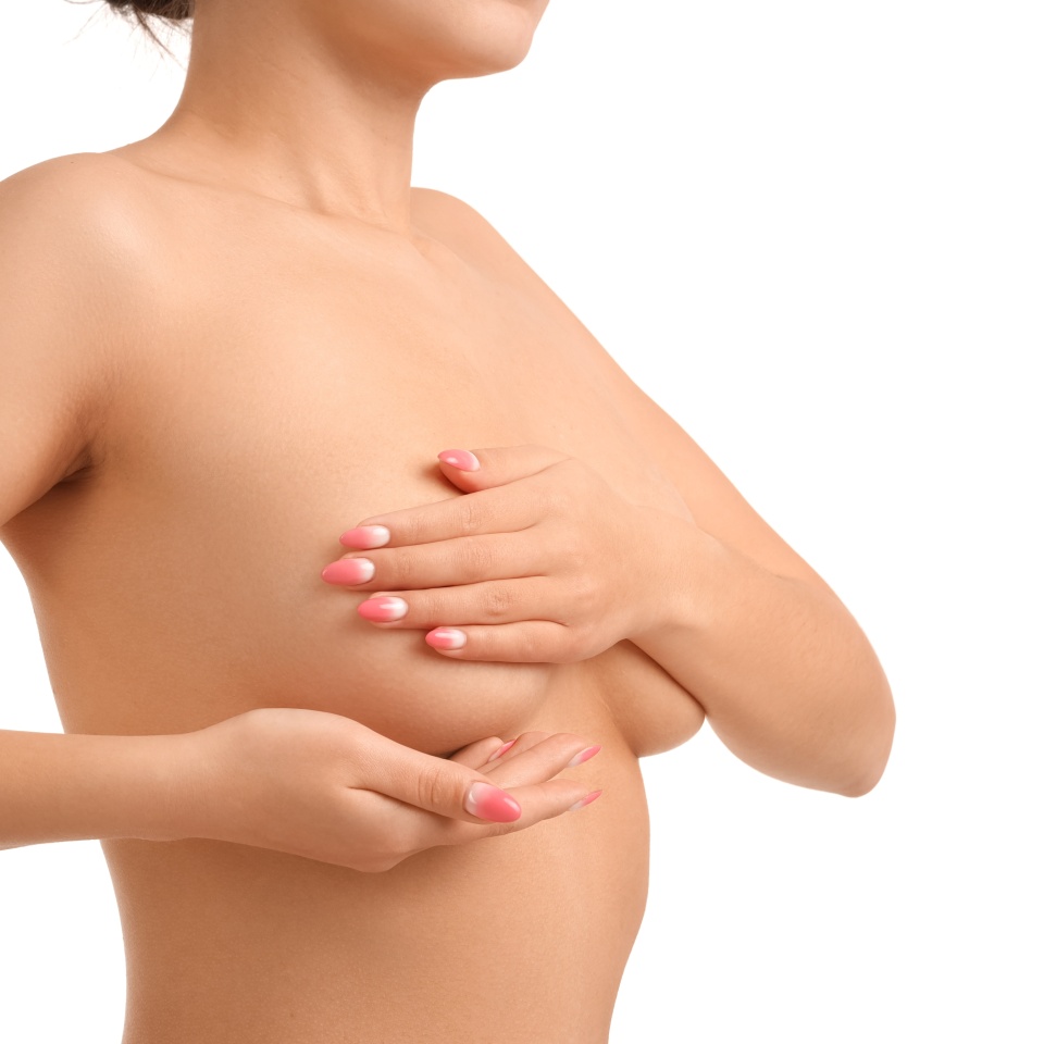 Naked young woman covering her breasts on white background, closeup
