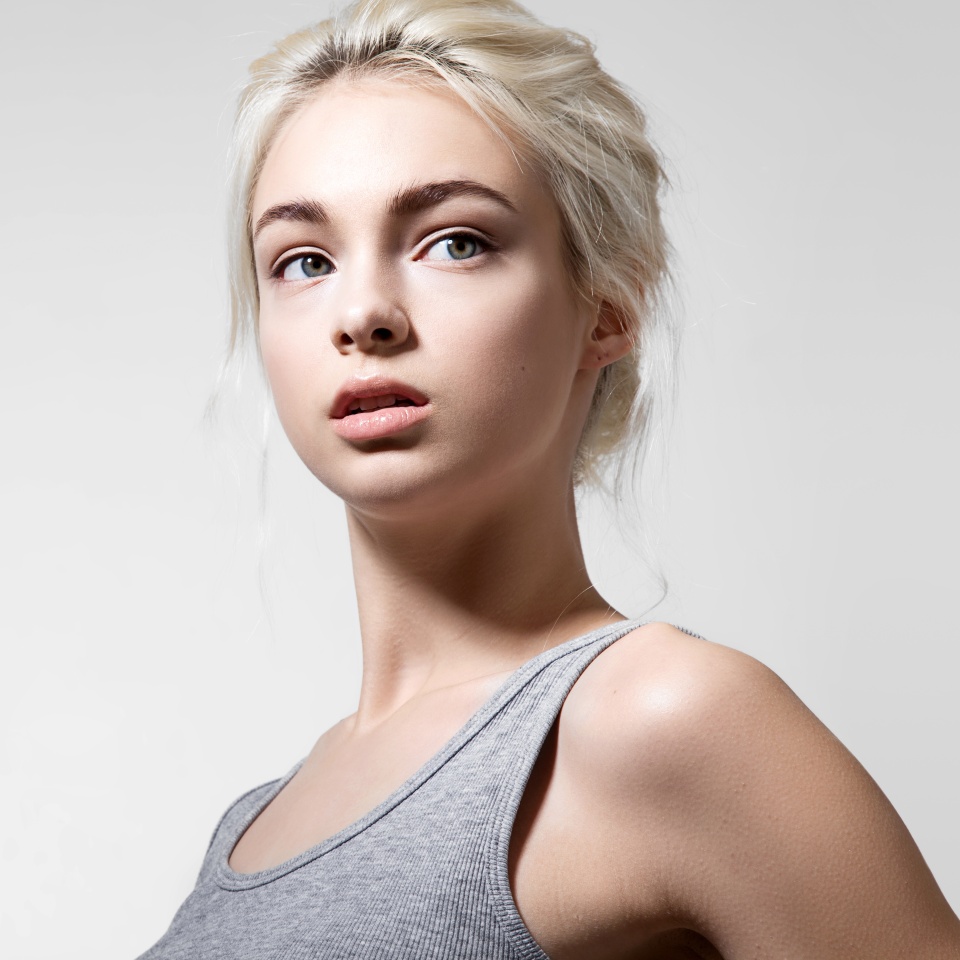 Girl with a good clean skin of the face in a gray shirt on a light background