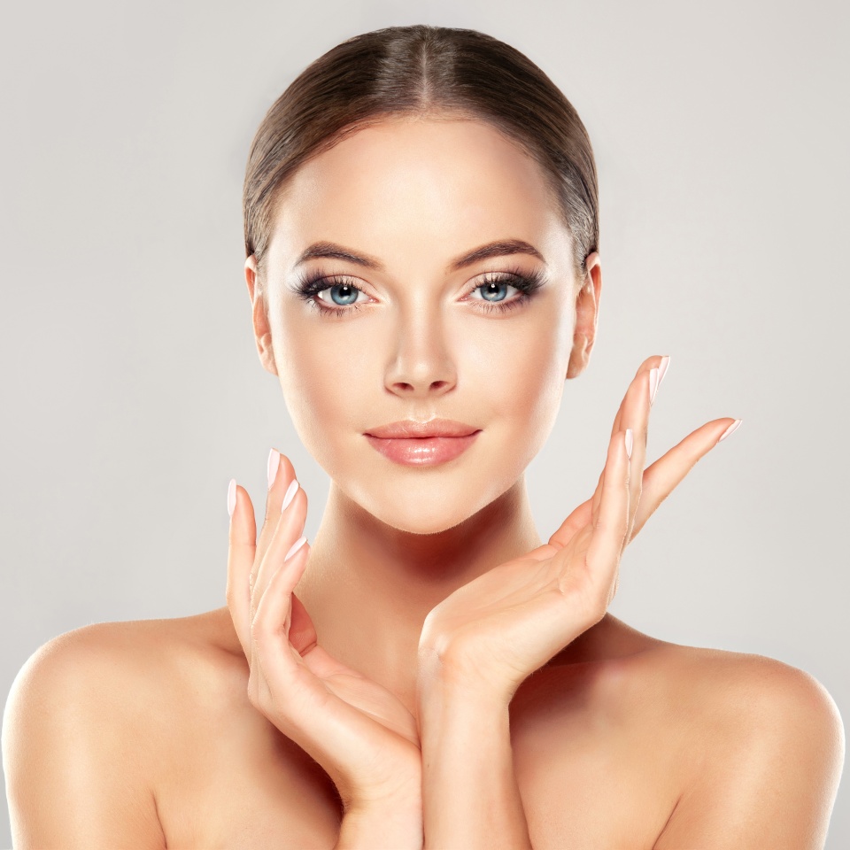 Beautiful Young Woman with Clean Fresh Skin touch own face . Facial treatment . Cosmetology , beauty and spa .