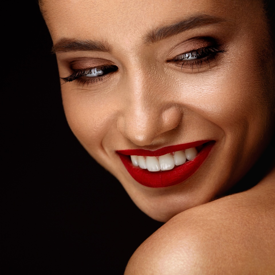 Fashion Makeup Model. Portrait Of Beautiful Glamourous Young Woman With Perfect Makeup, Long Eyelashes, Red Lips And Smooth Skin. Sexy Girl With Beauty Face On Dark Background. Cosmetics Concept
