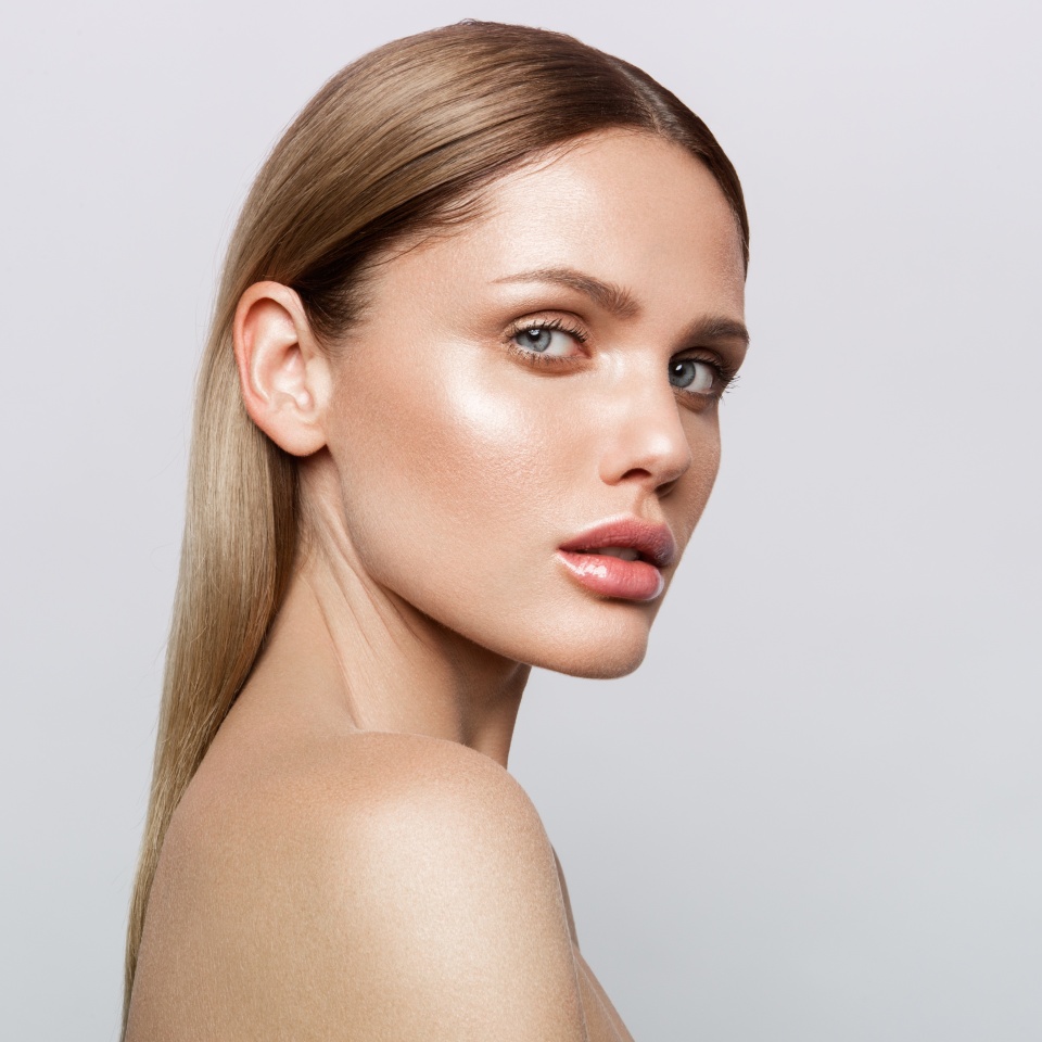 Beauty portrait of model with natural make-up. Fashion shiny highlighter on skin, sexy gloss lips make-up