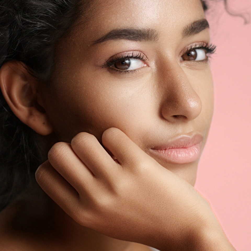Close up video of a happy and relaxed young woman with perfect olive skin fixing her wavy black hair isolated on white