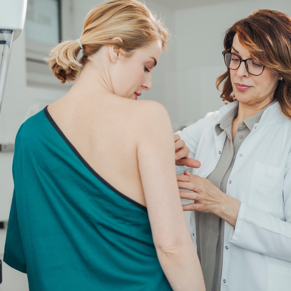 Woman gynecologist doing breast exam to her patient.