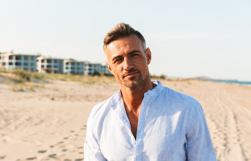 Portrait of a handsome man in shirt standing at the beach